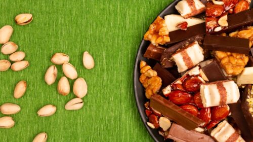 A plate of assorted chocolates and nuts on green background.