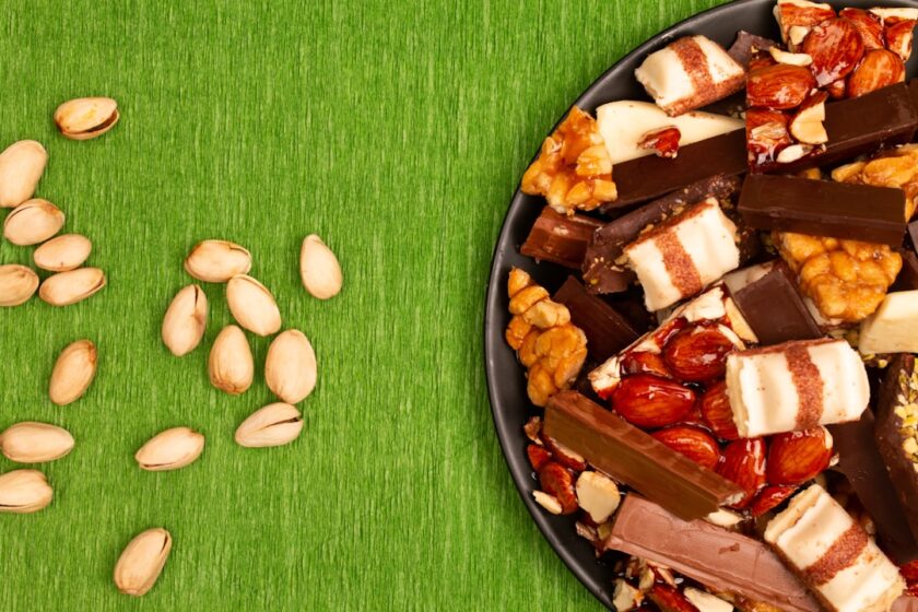 A plate of assorted chocolates and nuts on green background.