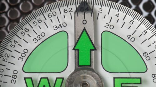 a close up of a compass with a green arrow