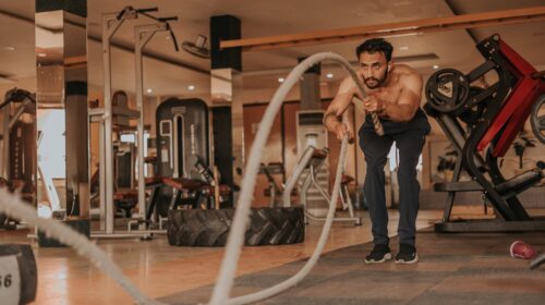 a shirtless man in a gym holding a rope