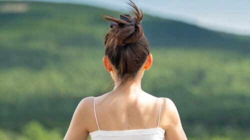 a woman sitting on top of a rock with her hair in the air