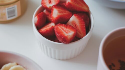 a bowl of sliced bananas and strawberries next to a bowl of sliced bananas