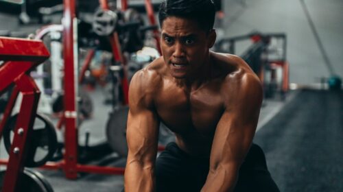 muscled man holding two black ropes
