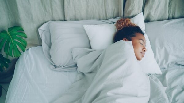 A young woman sleeping peacefully in a white bed.